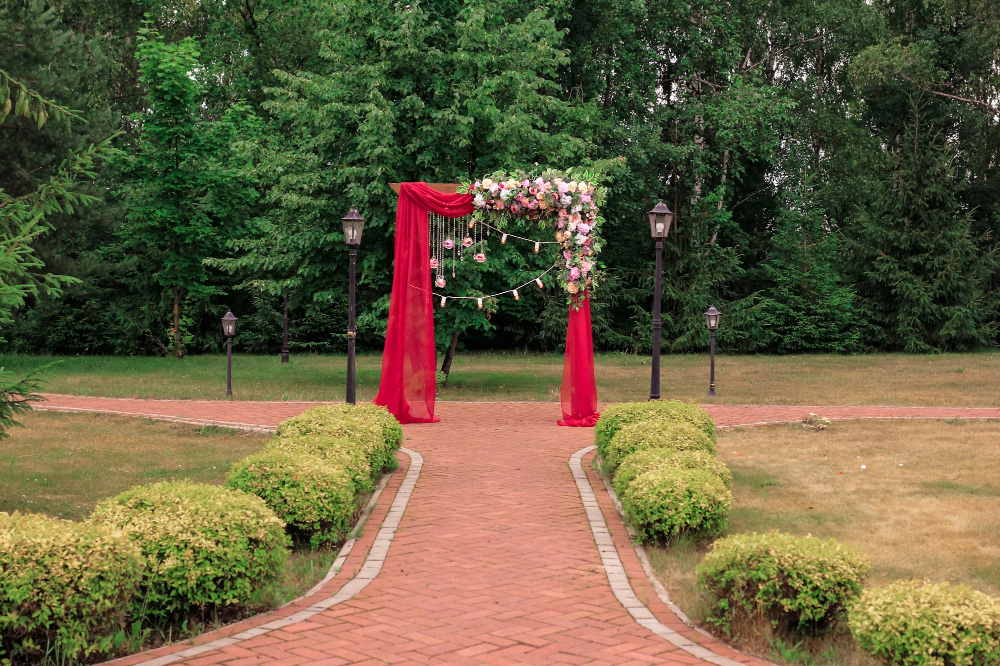 A wedding bright red arch decorated with flowers. Beautiful wedding decor for newlyweds.